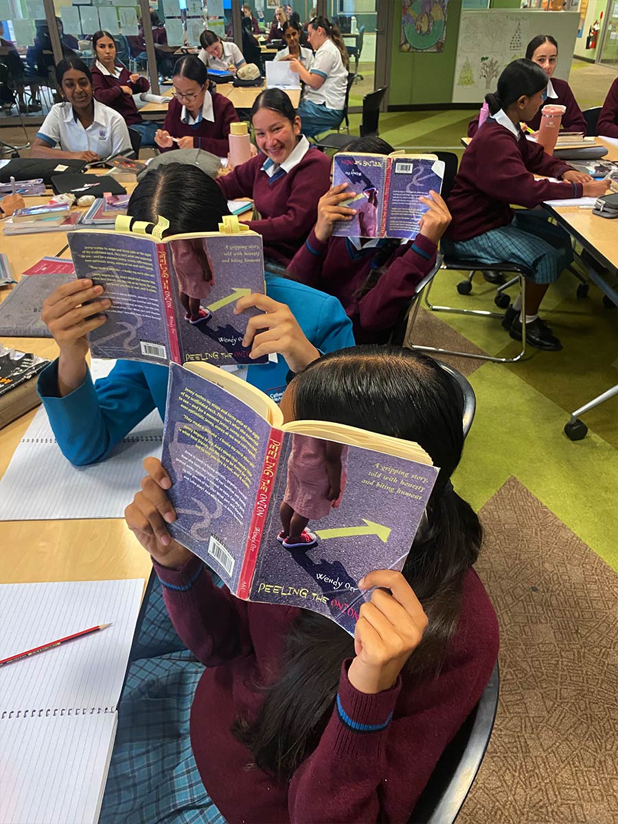 Year 8 English students covering their face with 'Peeling the Onion' Book