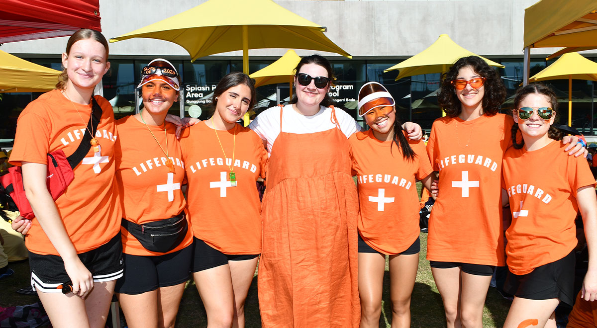 Six Catherine McAuley Westmead students, dressed as lifeguards, posing with their teacher