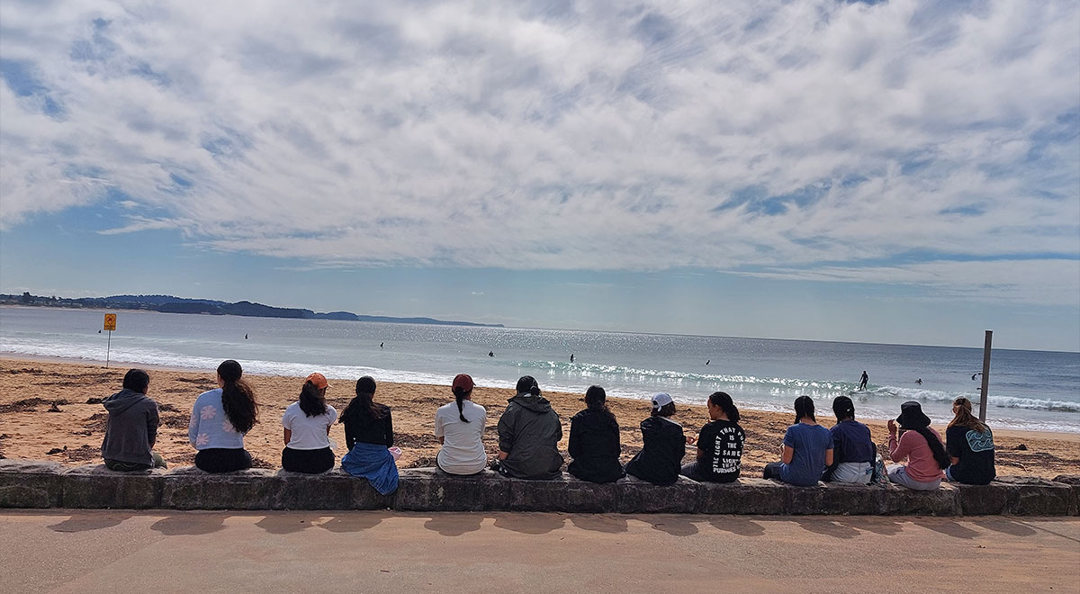 Mercy students sitting together on the beach