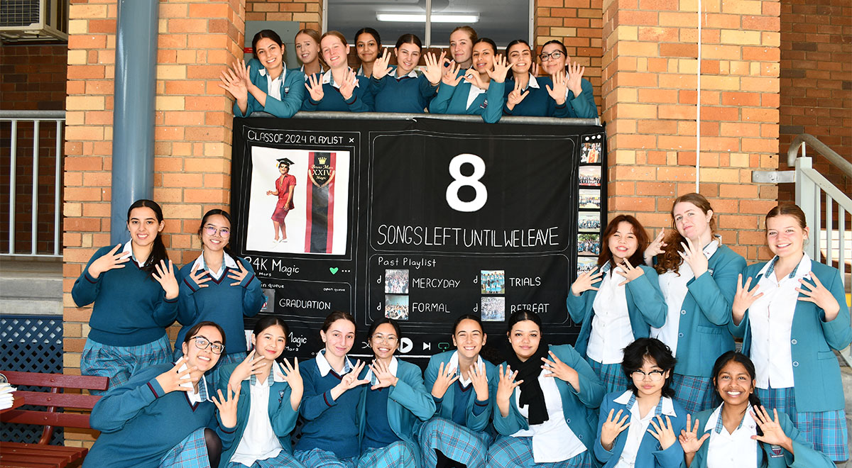 Senior students holding up a banner reading "8 Songs left until we leave"