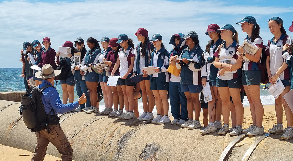 Students from Catherine McAuley Westmead standing on a pipe at Collaroy Beach excursion