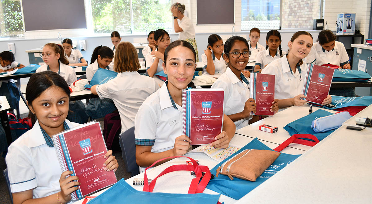 New Year 7 Catherine McAuley Westmead students holding their induction booklets