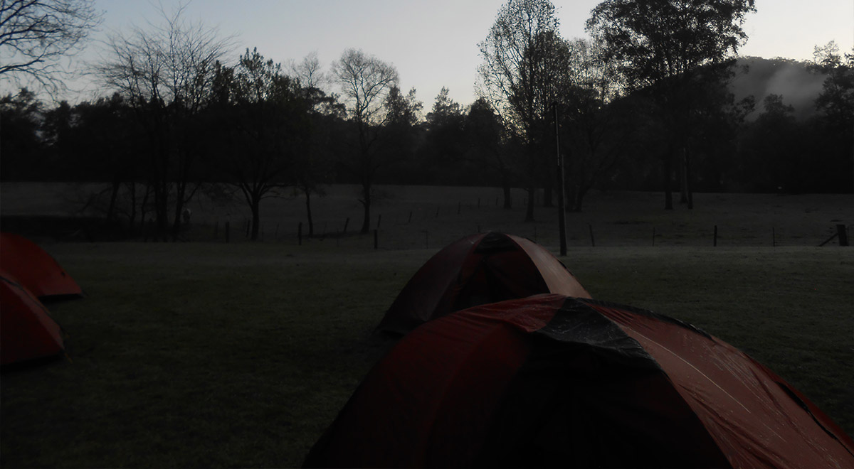 Duke of Ed camping. There is a foggy mountain range in the background.