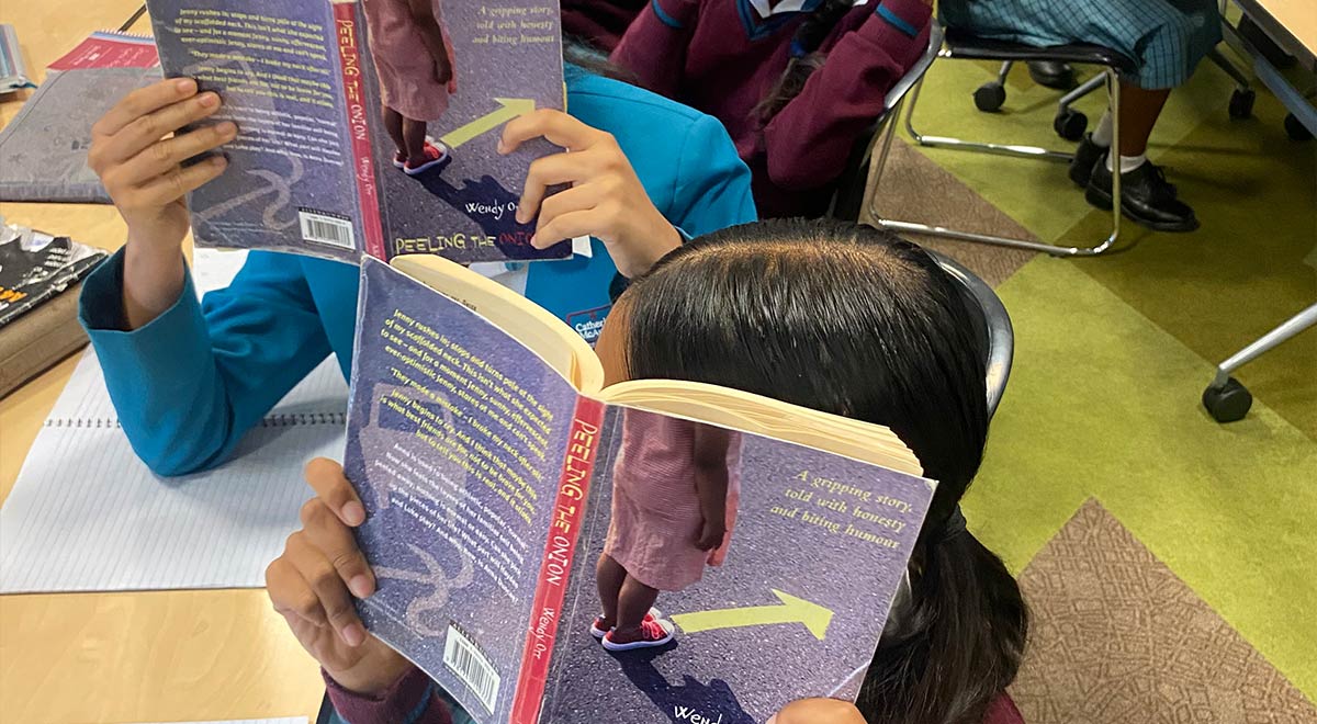 Year 8 English students covering their face with 'Peeling the Onion' Book