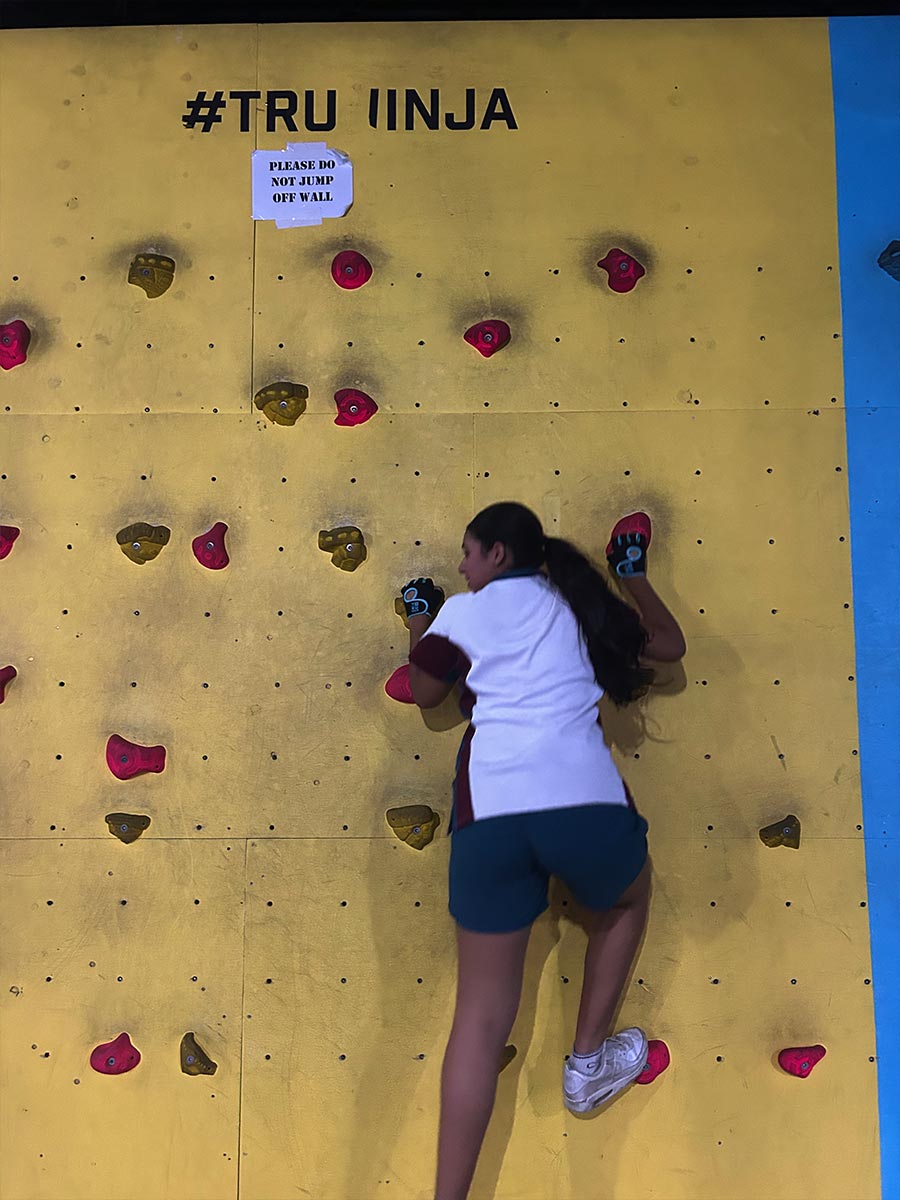 Catherine McAuley Westmead student climbing up a rock climbing wall at Tru Ninja Warrior