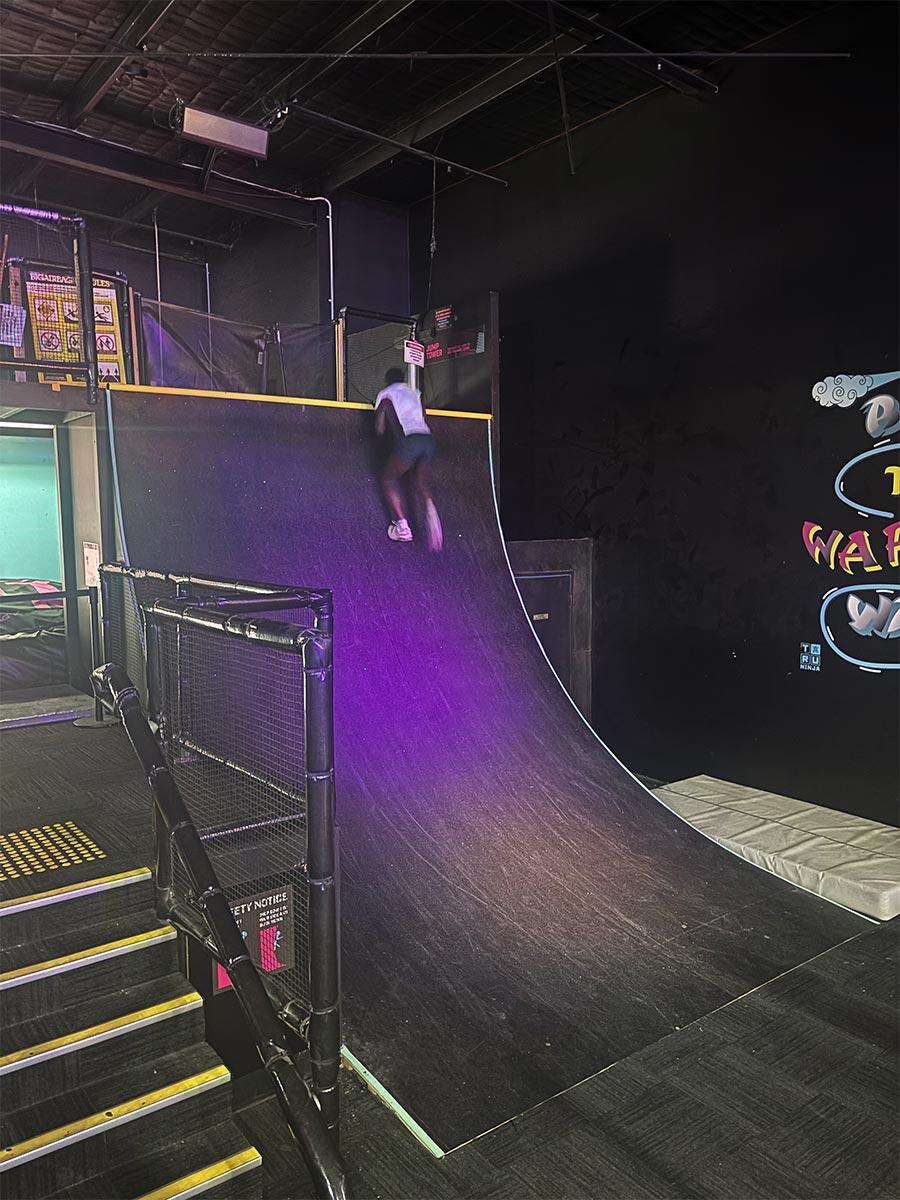 Catherine McAuley Westmead student climbing up a ramp at Tru Ninja Warrior