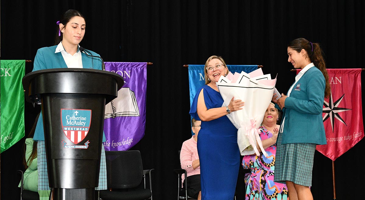 Kirsten Andrews presented with flowers by school captains IWD assembly
