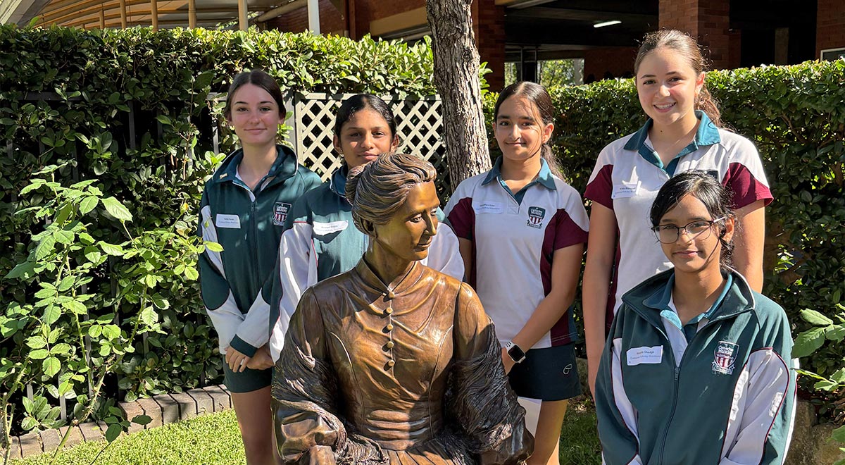  Some of the Year 9 students who attended with a statue of Catherine McAuley in the grounds of OLMC