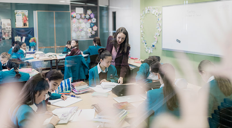 Dedicated teacher assisting Catherine McAuley Catholic College Westmead students in a study space