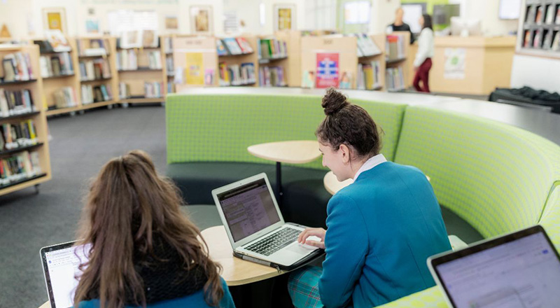 Catherine McAuley Catholic College Westmead Student sitting in library and using BYOD MacBook